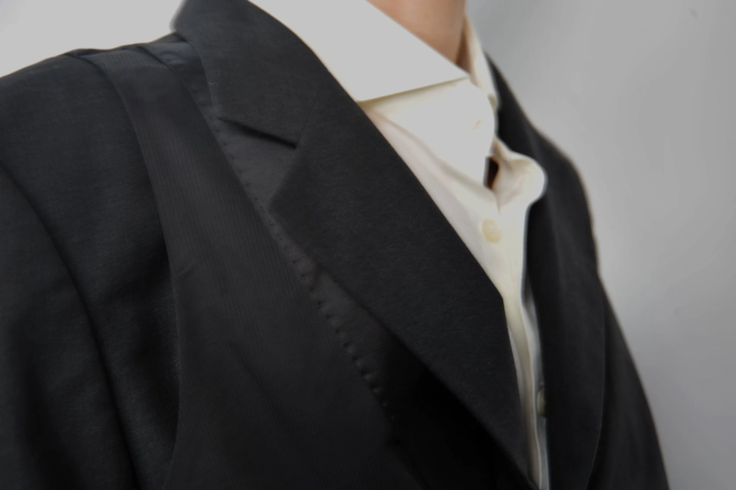 Close-up of a person wearing a dark suit jacket over a white shirt.