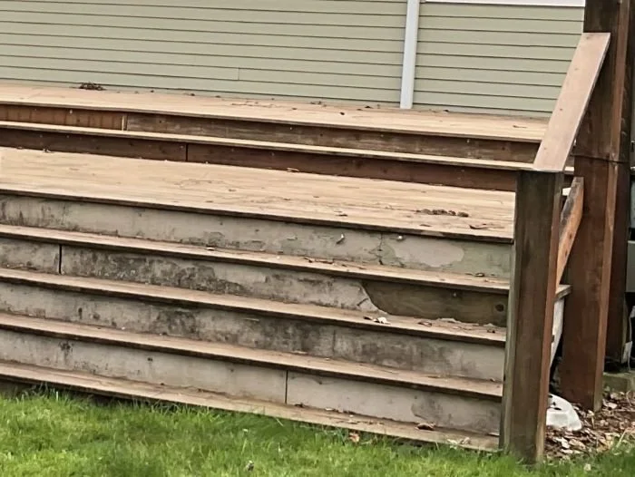 Aging wood deck in Maple Valley before structural deck replacement, showing deteriorated framing, worn stairs, and an outdated railing system.