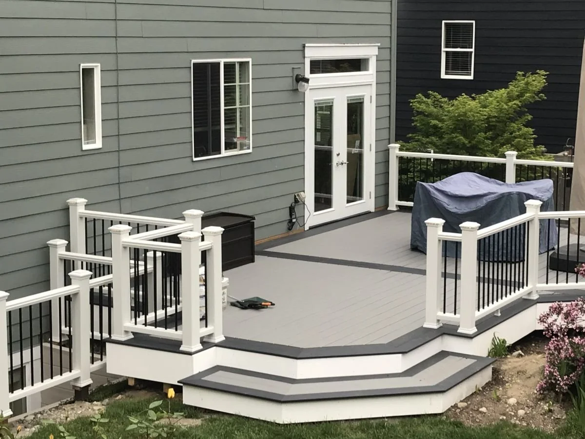Custom composite deck replacement in Auburn featuring black aluminum railings, wide stairs, and structural framing designed for long-term performance.