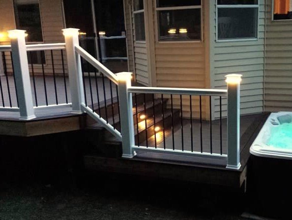 Metal deck post cap and step lighting installed near stairs and hot tub at night