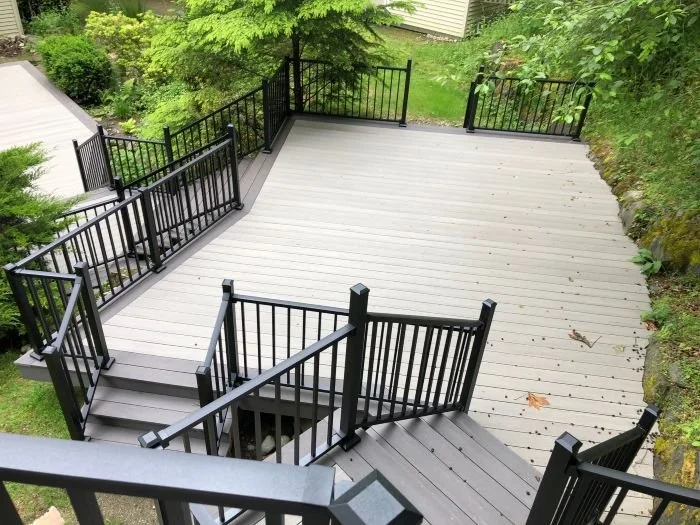 Multi-level deck with tiered platforms, stair transitions, and continuous metal railings on a sloped property