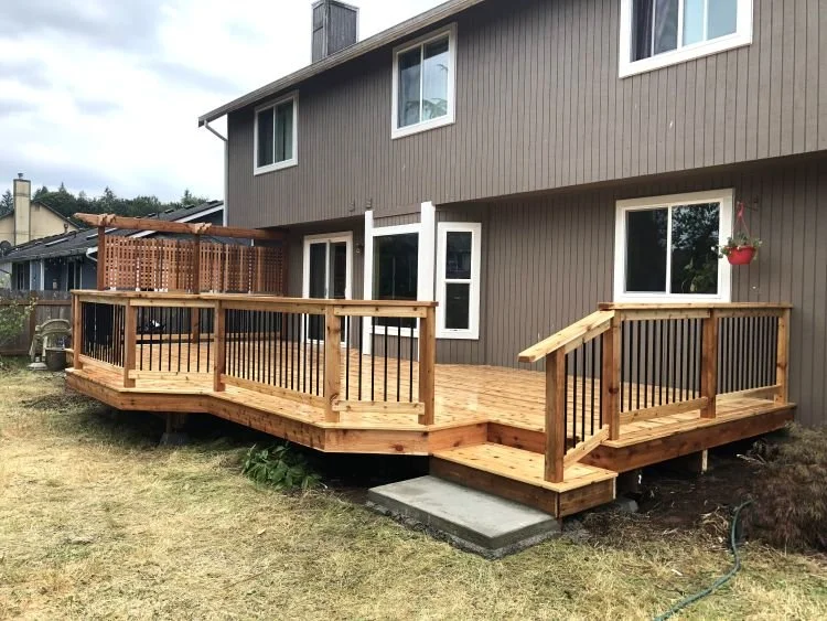 Custom cedar deck designed for a sloped backyard with black aluminum railings in Covington, WA.