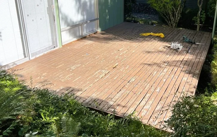 Worn wood deck before replacement in Renton WA showing weathered boards and surface deterioration from moisture exposure