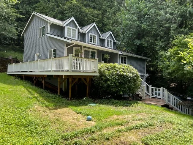 Elevated deck construction wrapping a home with stair access on a sloped property