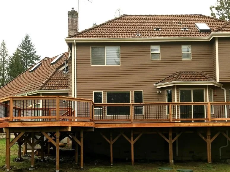 Custom cedar deck built by Petra Decks for a homeowner in Renton, WA featuring wood railing, black aluminum balusters, and elevated deck construction