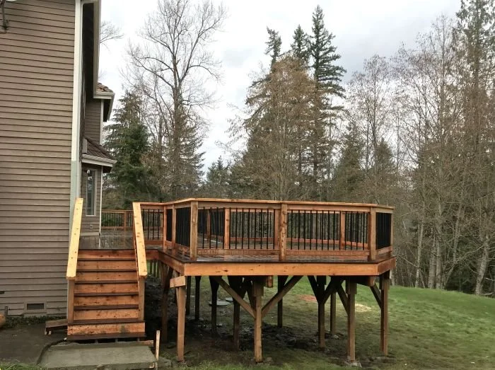 Deck construction in Covington WA on sloped yard showing elevated framing, support posts, and railing designed for structural stability and drainage