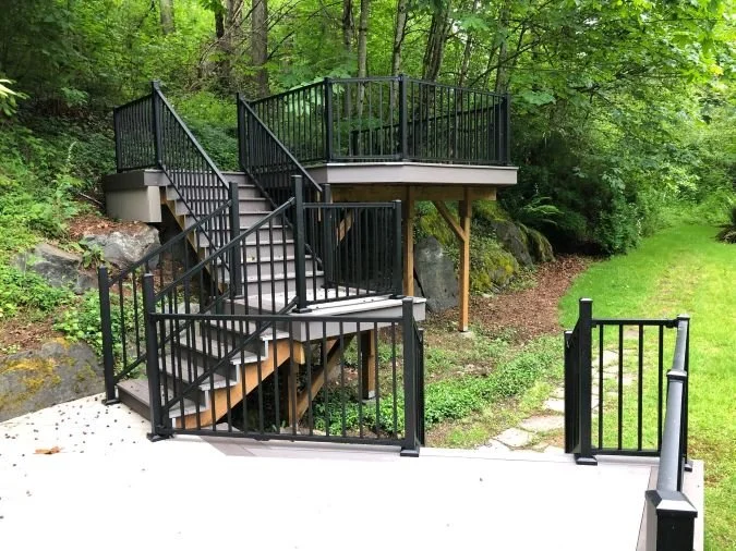 Multi-level deck with staggered platforms, integrated stairs, and metal railings on a sloped backyard