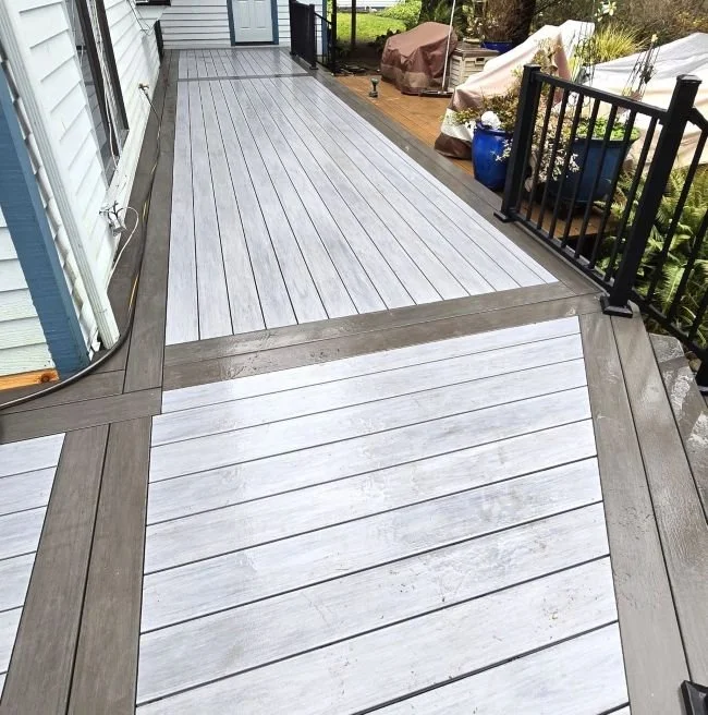 Custom PVC deck construction in Kent, WA featuring low-maintenance decking, contrasting picture-frame border design, and black metal railings for long-term outdoor durability.