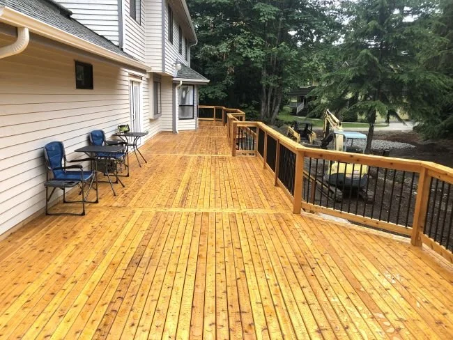 Custom cedar decking installation with natural wood grain and black aluminum railings in King County, WA.