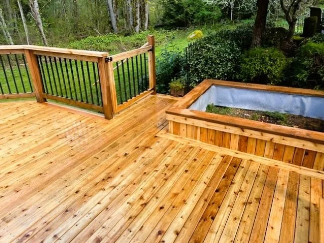 Cedar decking installed on a custom deck in Renton, WA featuring a built-in planter box and wood railing with black balusters.