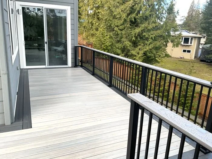 Custom composite deck with black aluminum railing built by Petra Decks for a hillside home in Issaquah, WA.