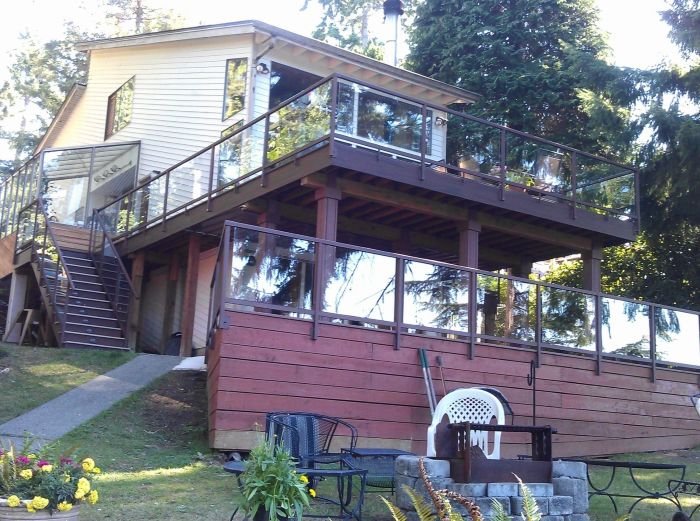 Multi-level elevated deck construction with stairs and guardrails on a sloped property