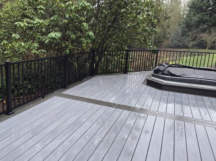 PVC composite deck replacement in Kent, WA with black metal railing and built-in hot tub area