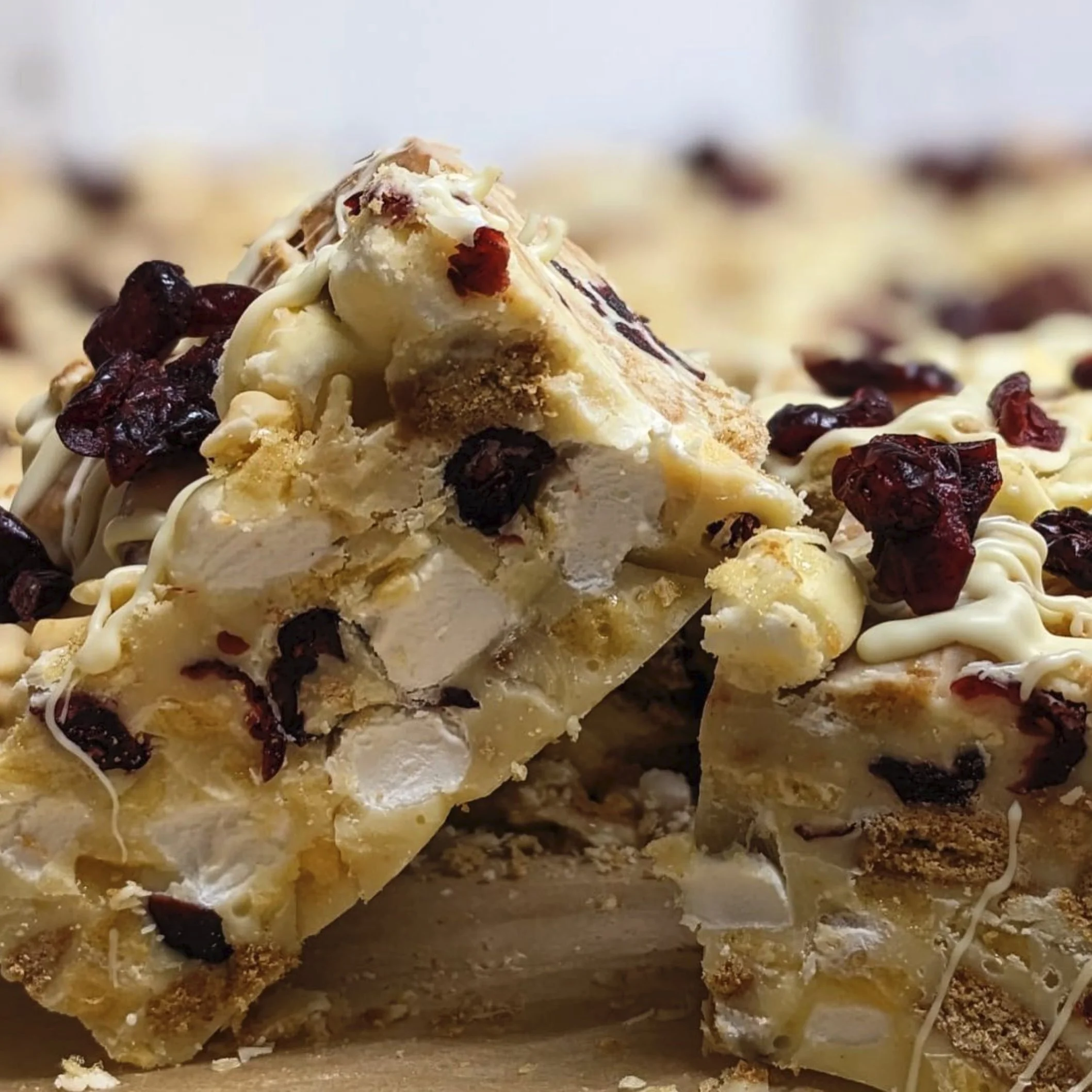 Close-up of a slice of white chocolate cranberry candy bark with dried cranberries, white chocolate, and crushed cookies.