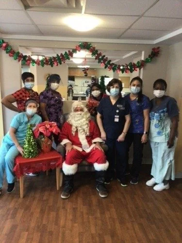 Group of young healthcare workers and Santa Claus celebrating Christmas in a decorated room.