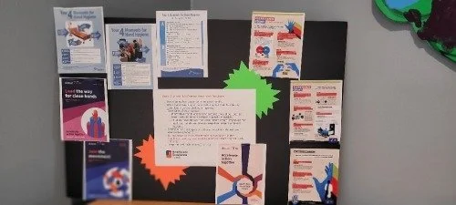 A bulletin board with various informational flyers, pamphlets, and posters pinned to it, including colorful paper decorations.