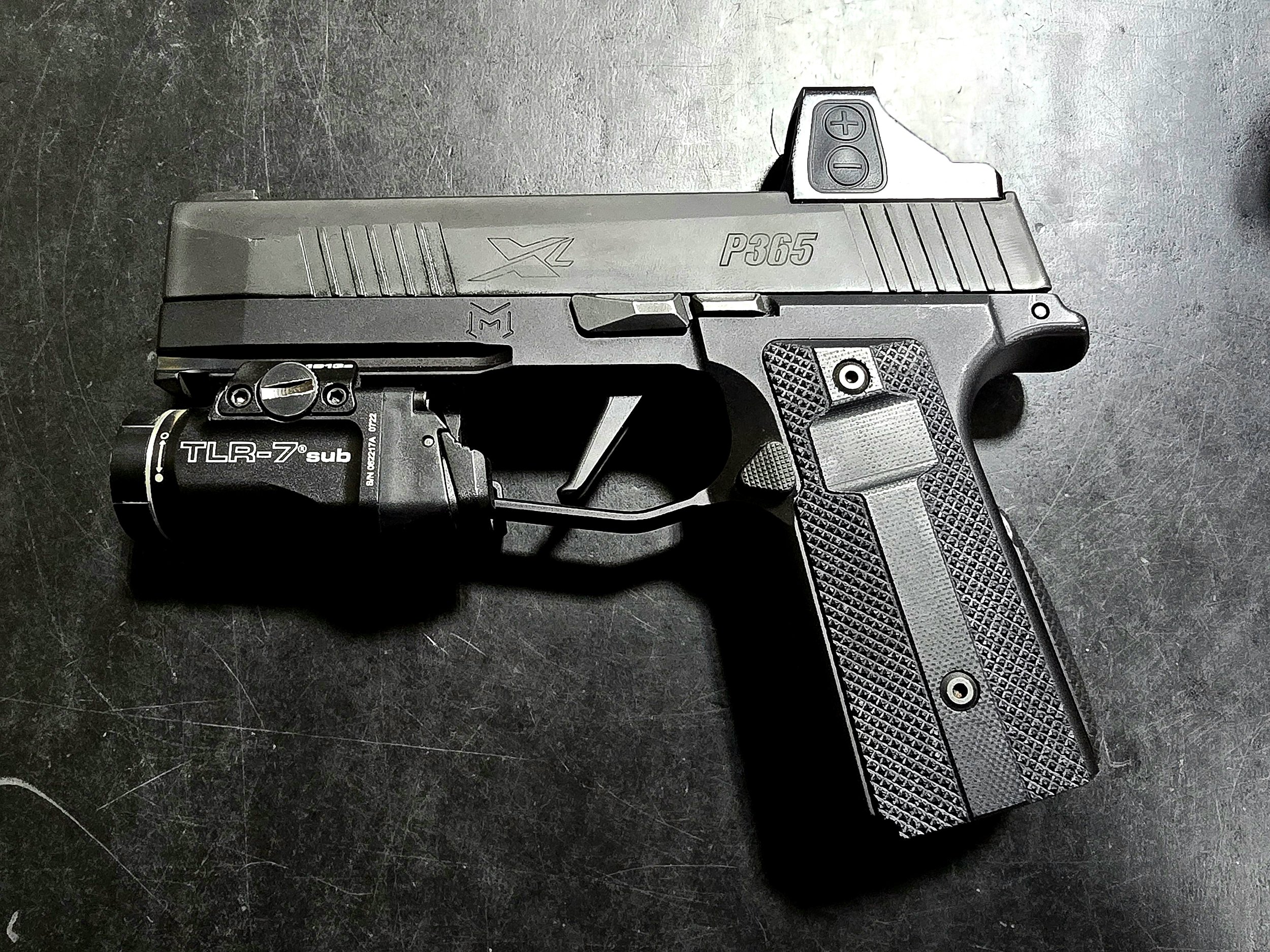 A semi-automatic pistol with a black grip, silver slide, and a mounted tactical flashlight attached under the barrel.