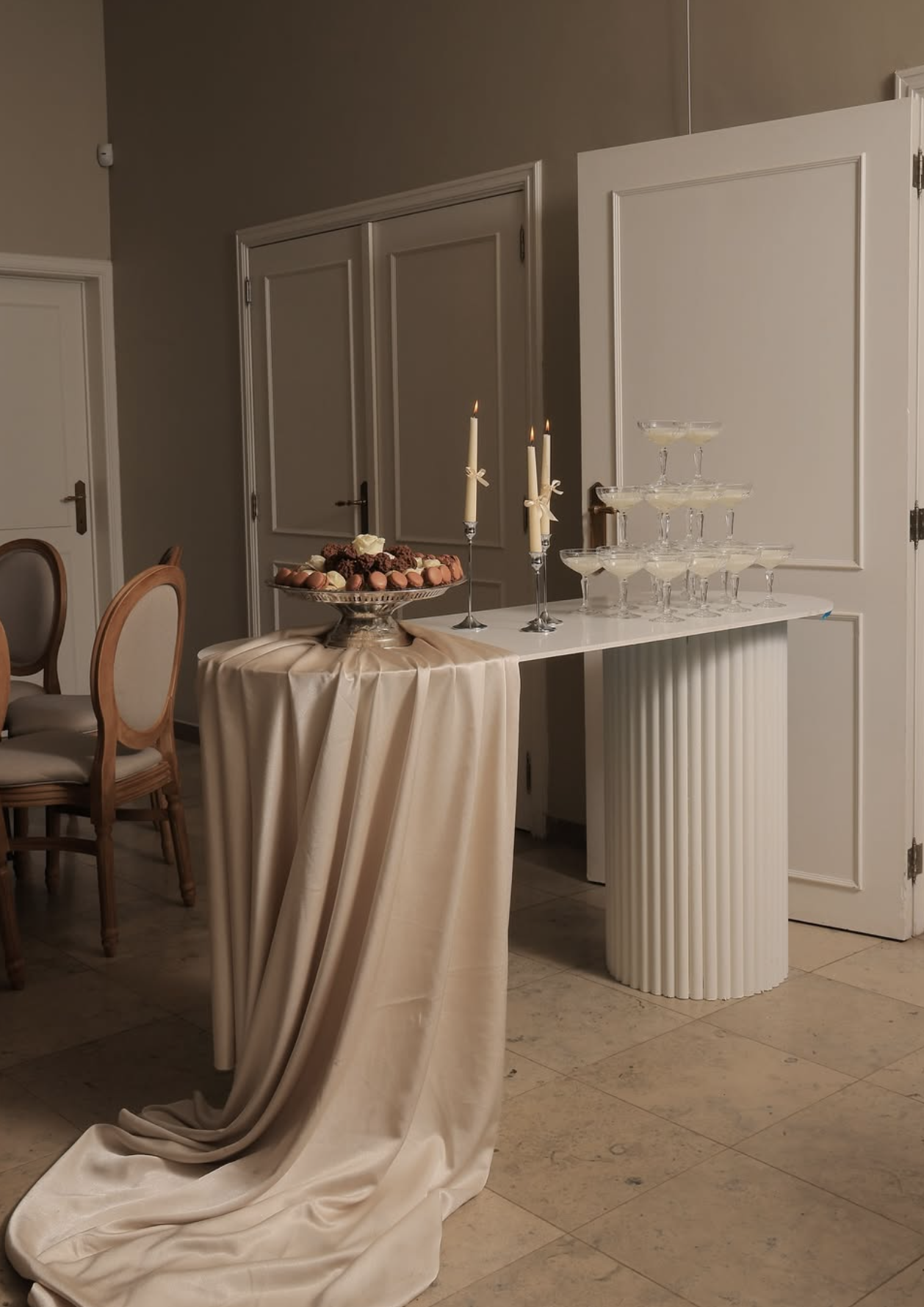 Elegante feesttafel met een champagne-ijsbad en dessert, met kaarsen, glazen en een ivoorkleurige doek.