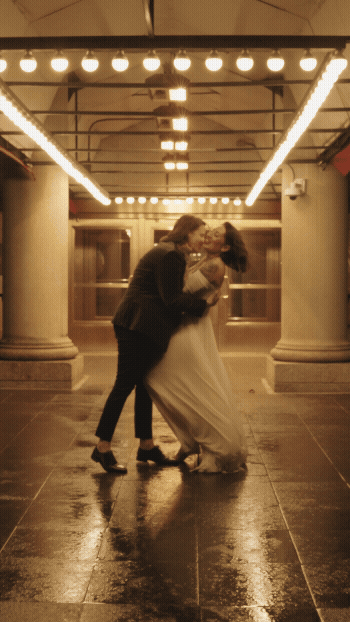 A couple dancing closely under warm lighting in a dimly lit indoor space.