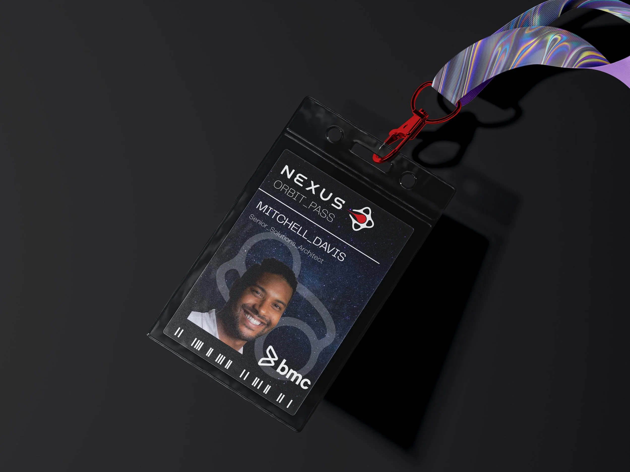 A black Nexus ID badge with a photo of a smiling man, named Mitchell Davis, labeled as Senior Solutions Architect, attached to a colorful lanyard with a red clip, placed on a black surface.