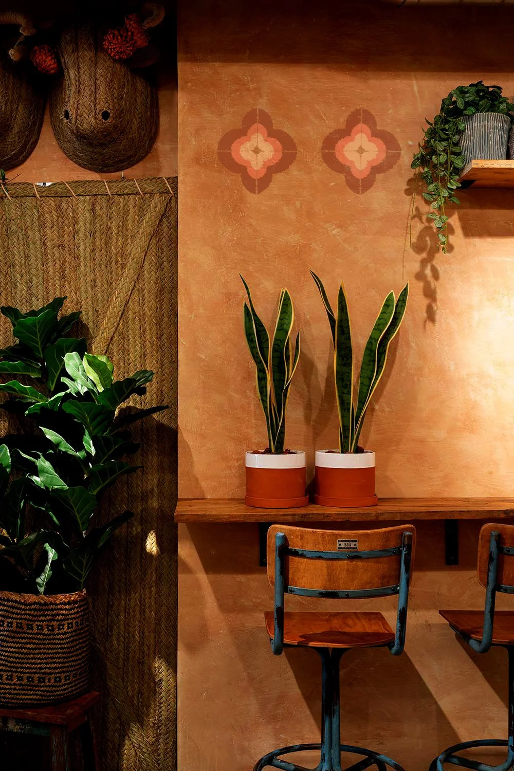 Interior of a cozy cafe or restaurant with potted plants, woven decor, and wooden furniture.