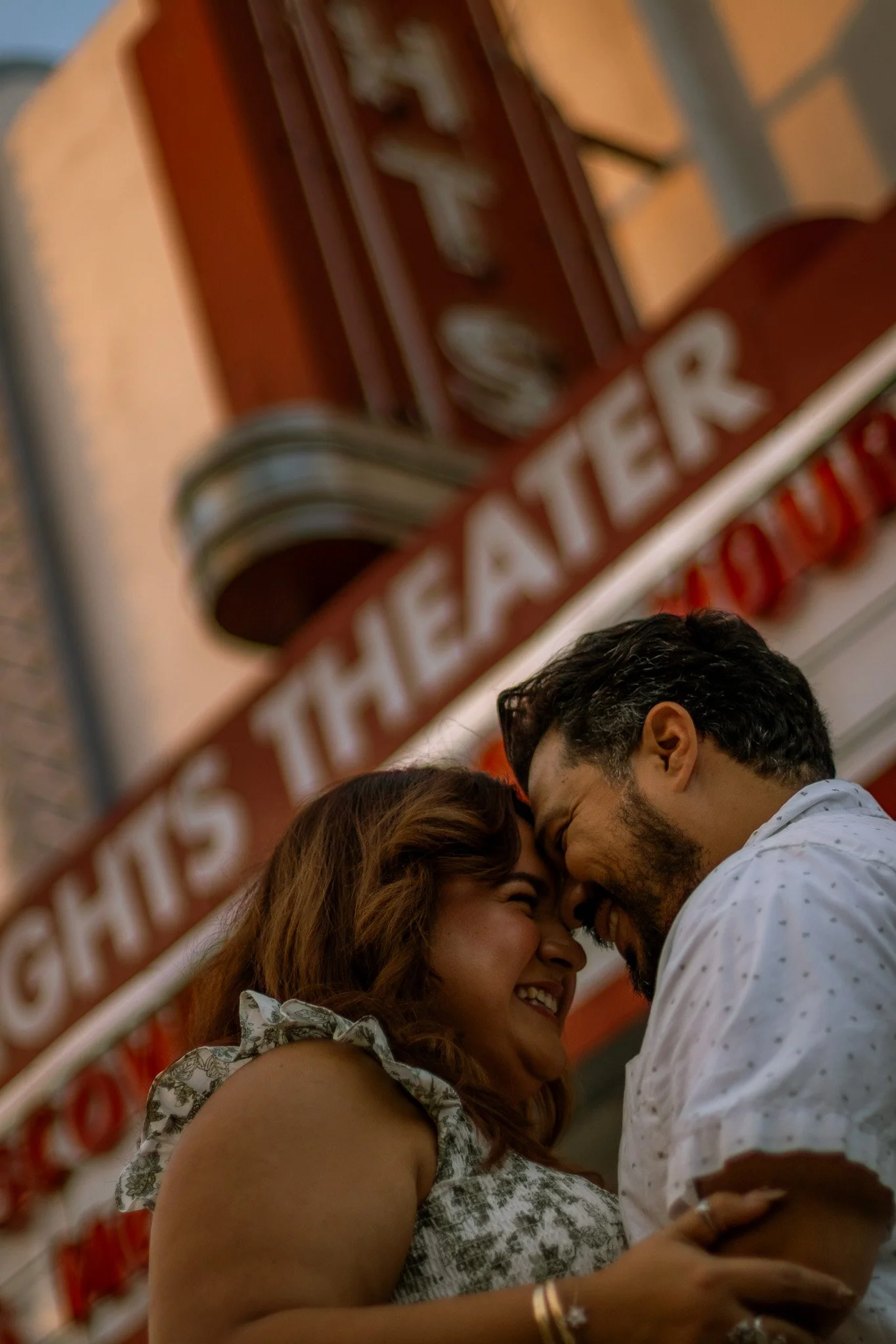 A couple sharing a joyful moment in front of a theater marquee sign.