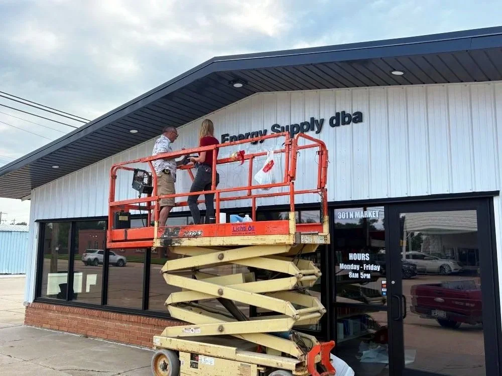 Michael Burger and Rebekah Smith installing letter signage for Lichti Oil in Shickley, NE