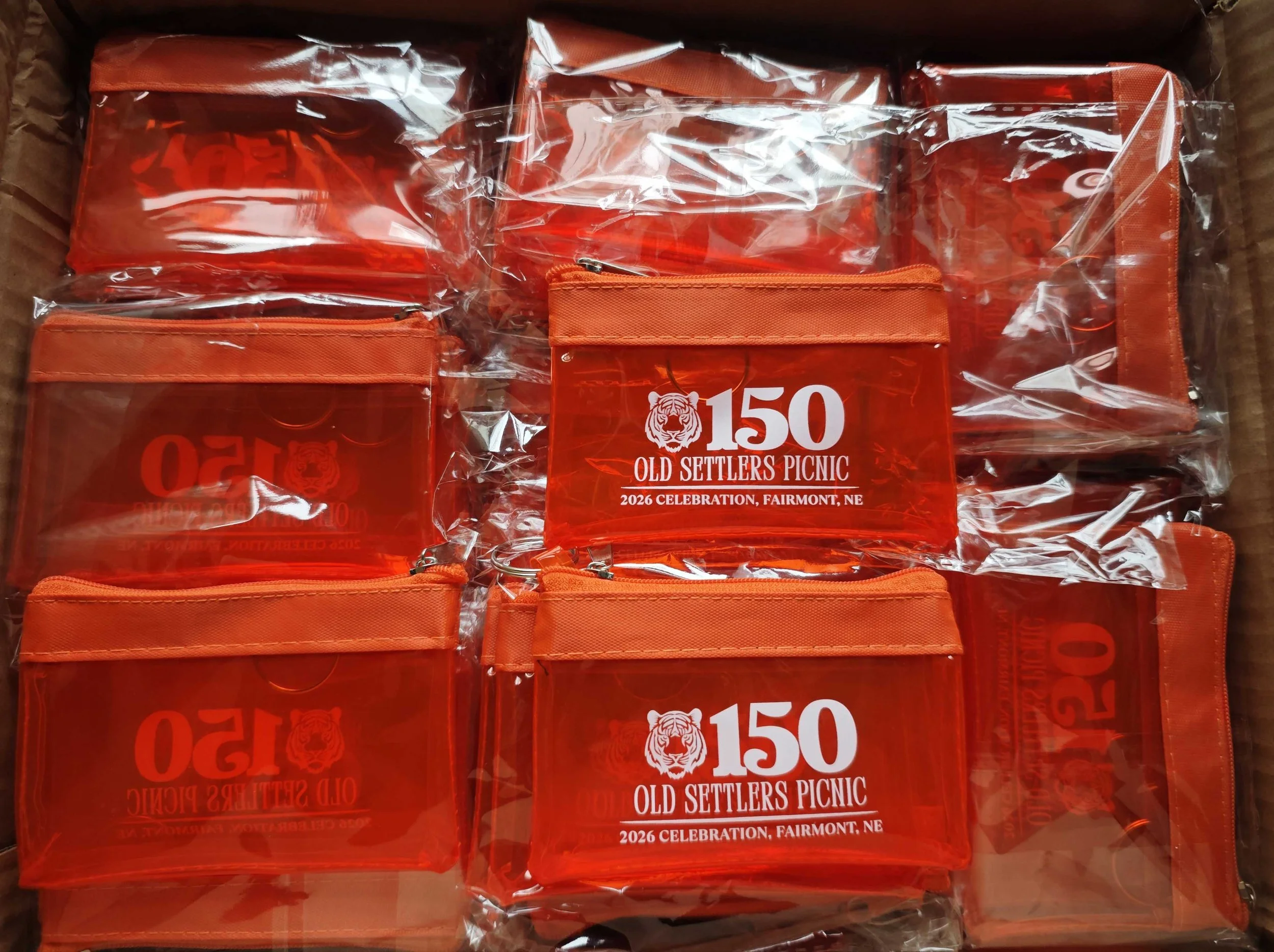 Packaged orange promotional items for Old Settlers Picnic in Fairmont, Nebraska, celebrating the 150th anniversary in 2026.