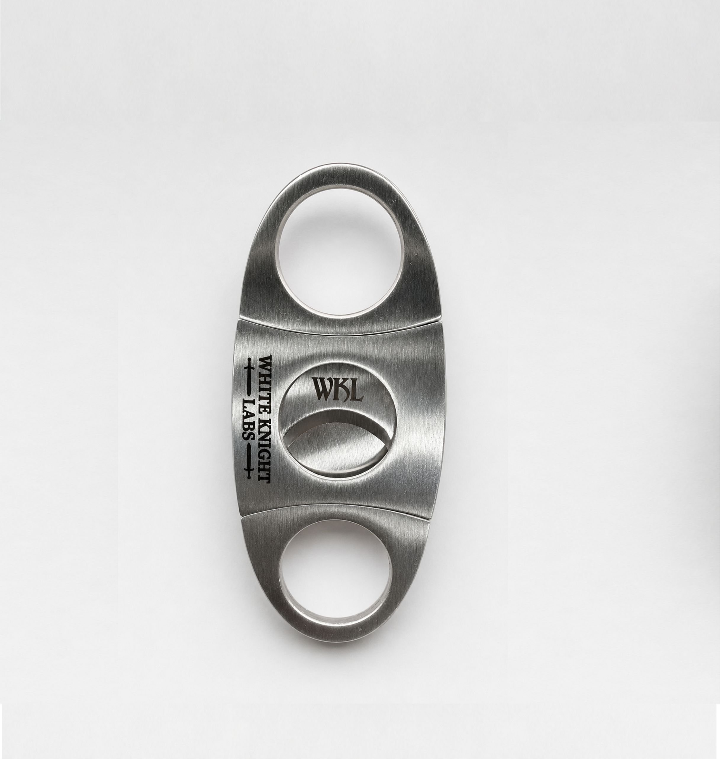 Close-up of a metallic Cigar Cutter on a white surface with engraving.