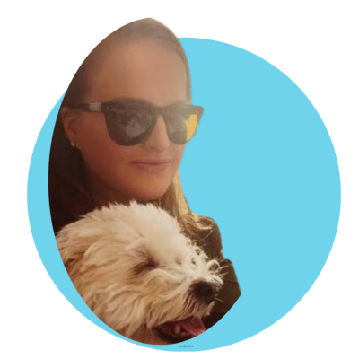 Woman wearing sunglasses and smiling with a white fluffy dog against a blue background.
