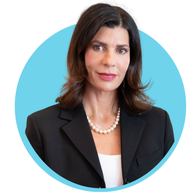 Professional woman with dark hair wearing a black blazer and pearl necklace, against a blue background.