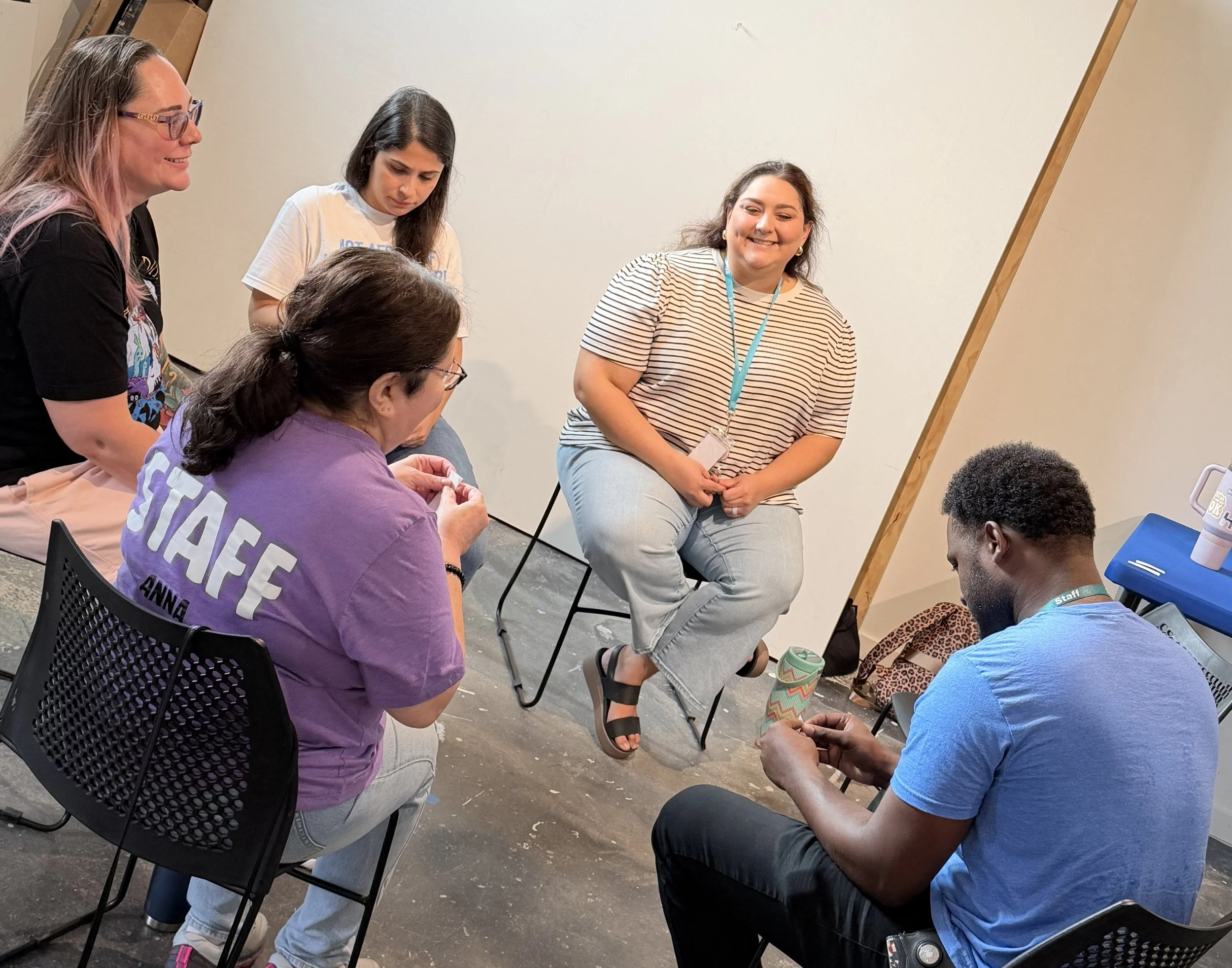 Group of diverse women sitting in a circle, engaged in conversation in a casual indoor setting.