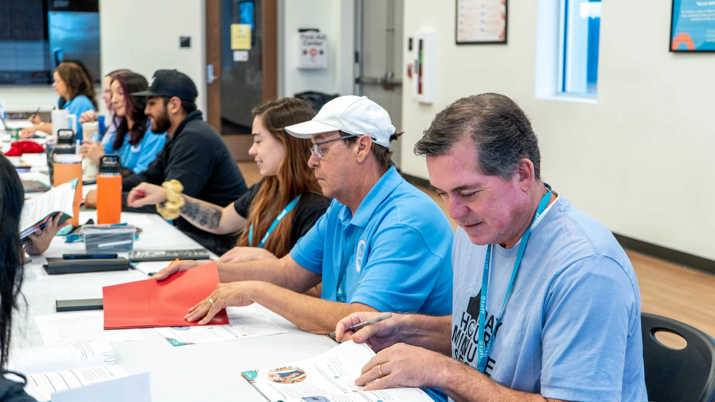Group of diverse people sitting at a table engaged in reading or writing during a meeting or workshop.