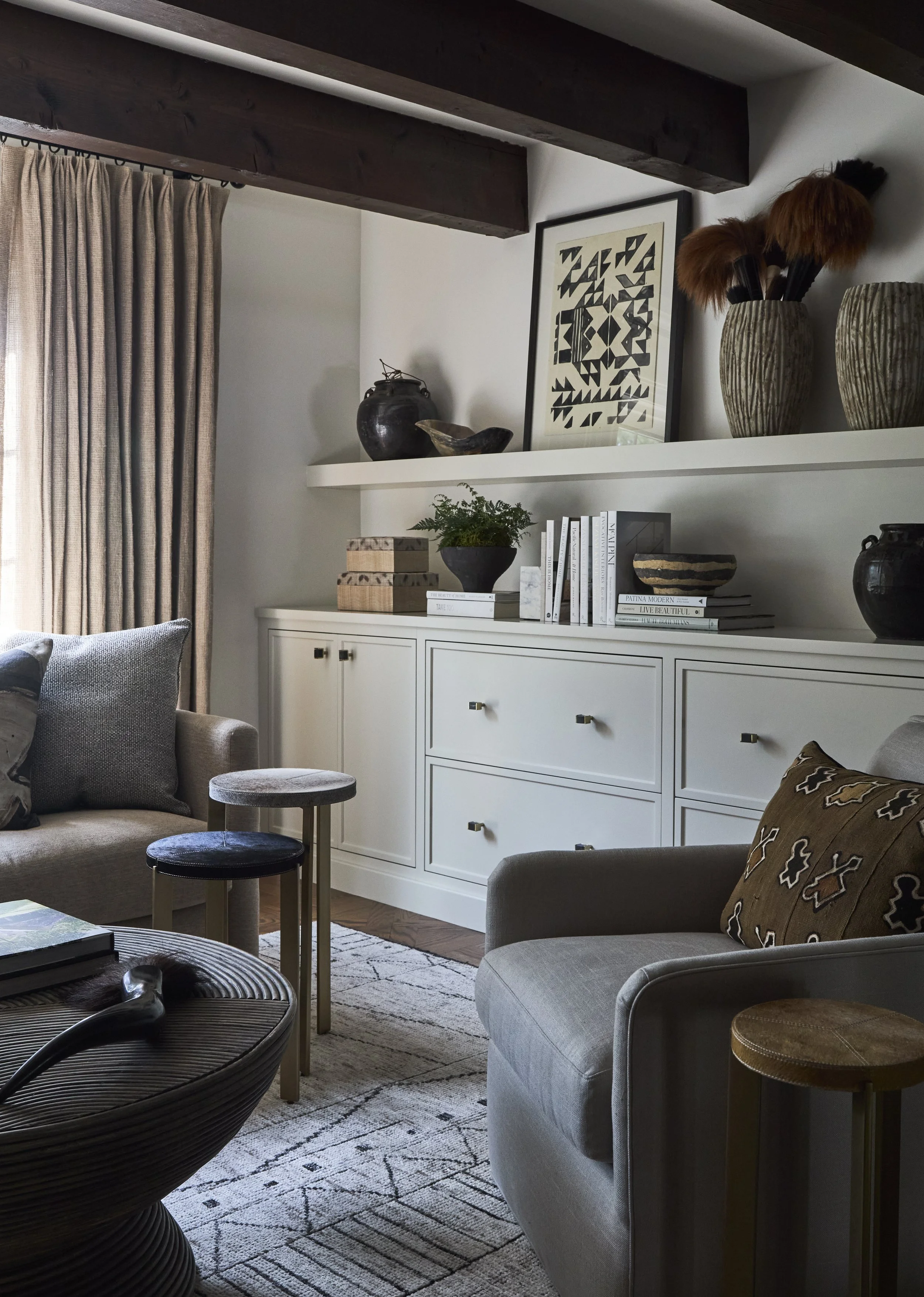 sitting room with white built-in cabinets. Inset panel with slim shaker cabinets. floating shelf. Large reclaimed beams in sitting room.