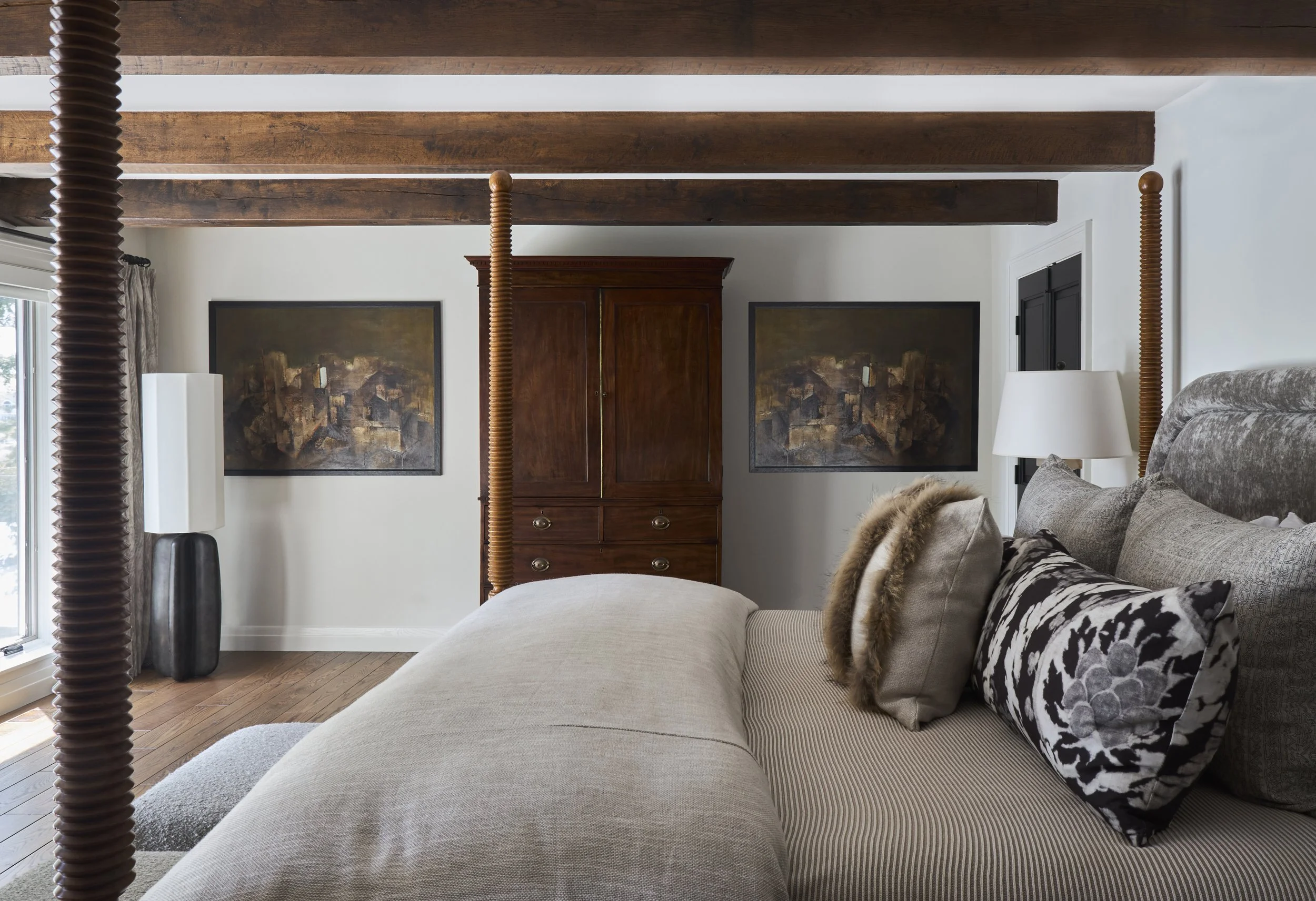reclaimed beams in bedroom, vintage armoire in bedroom. Large artwork in bedroom. Four-poster bed with turned spool legs.