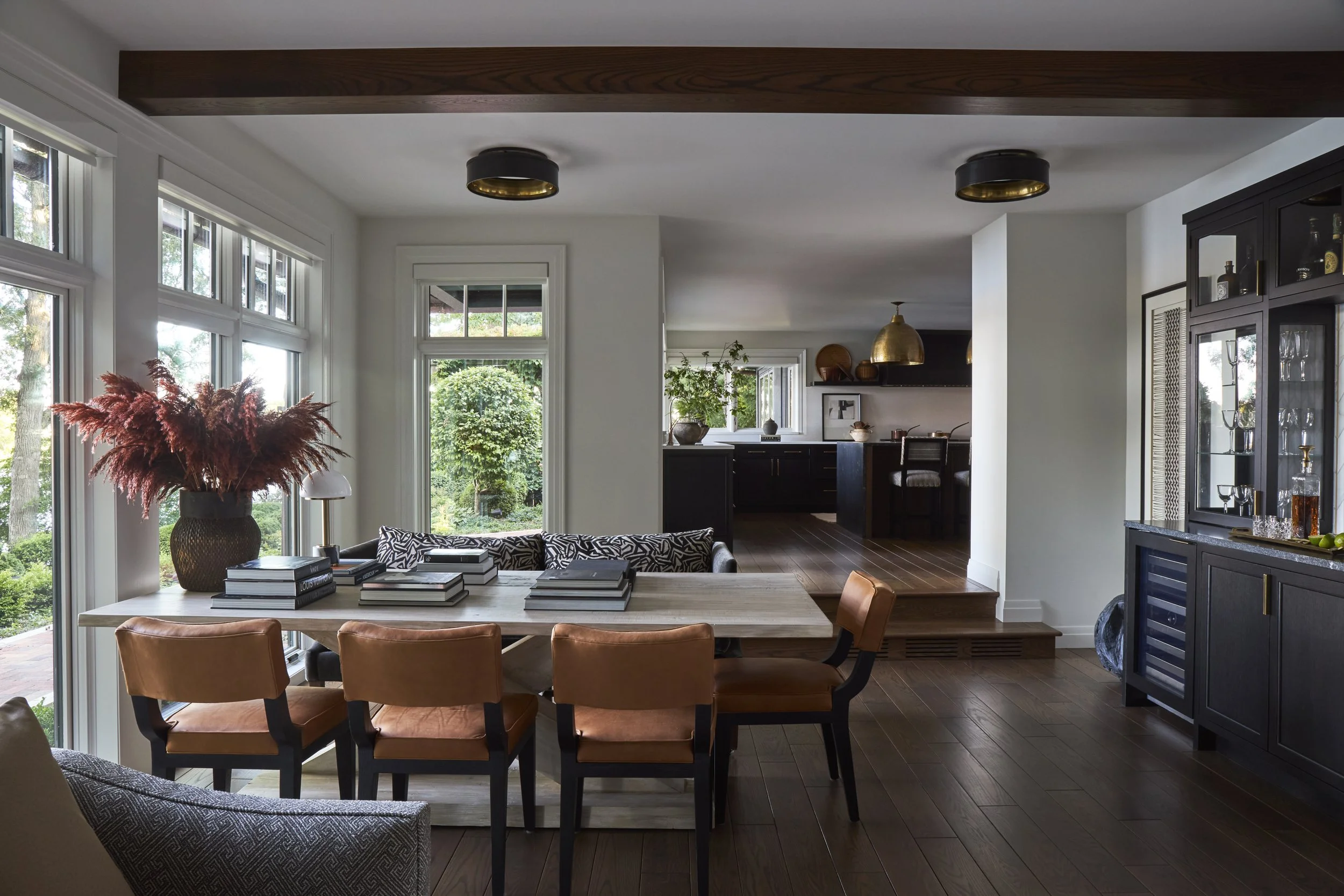 Dining table with leather chairs and settee bench seating. Large beam over dining table, no chandelier over table. Floor to ceiling windows in dining room.