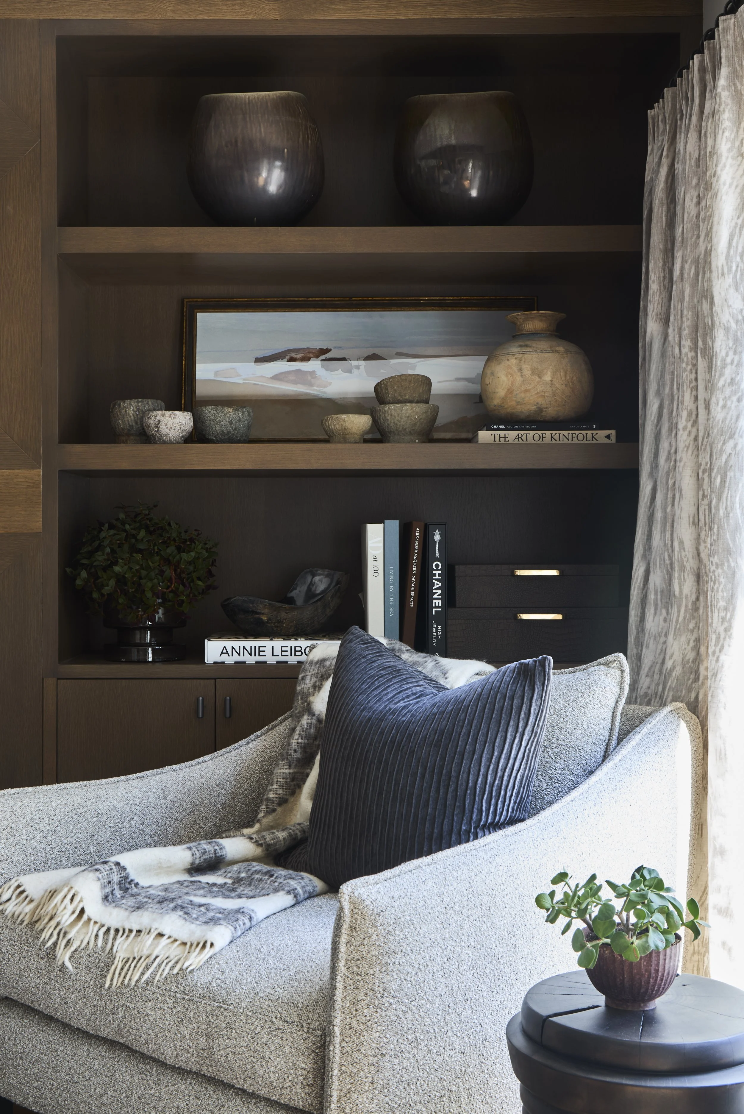 Swivel chair in reading nook. Built-in bookshelf stained dark with small bowls on shelves.