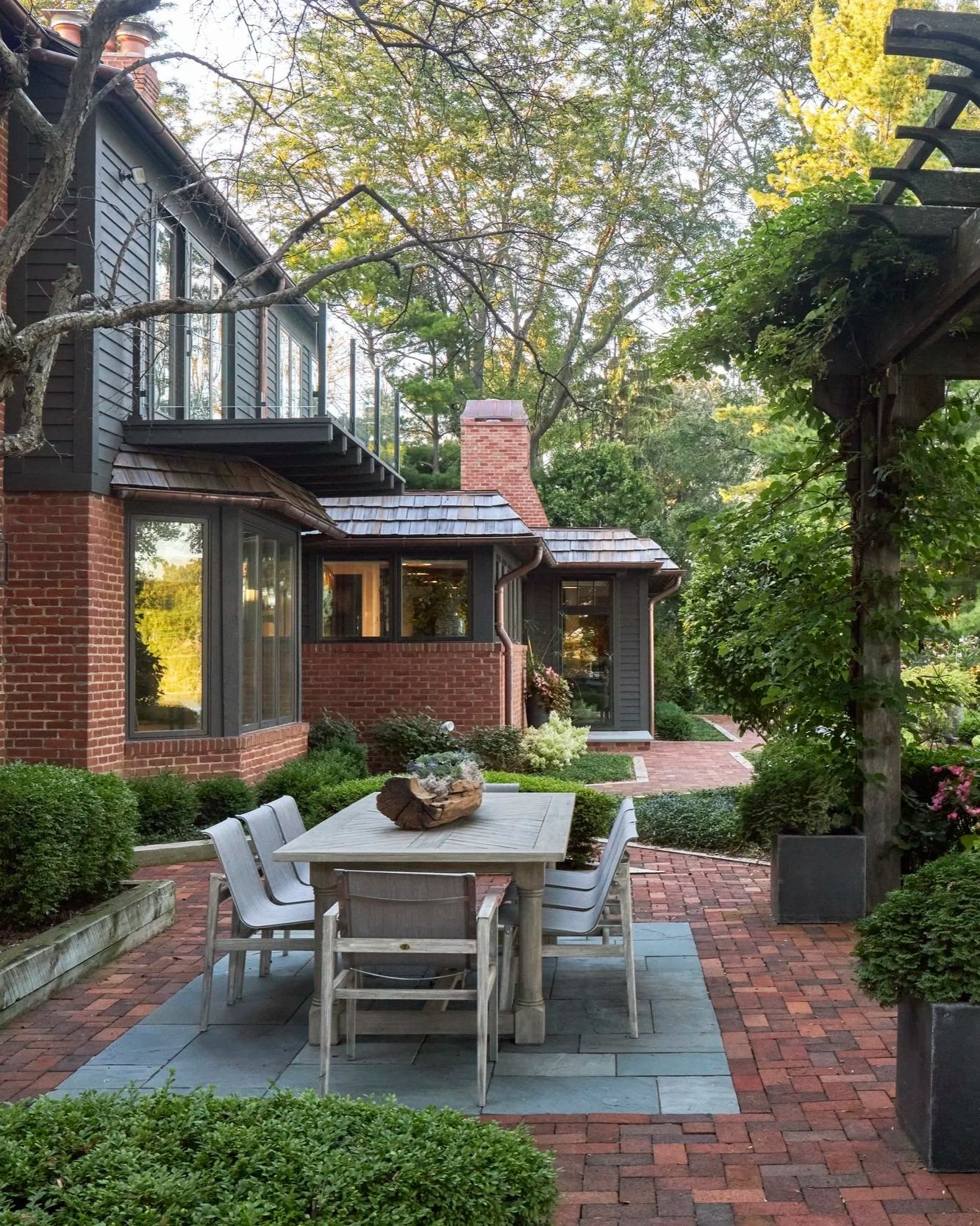 Outdoor patio with dining table and chairs, outdoor table seating for 8. Pergola with foliage and planters.