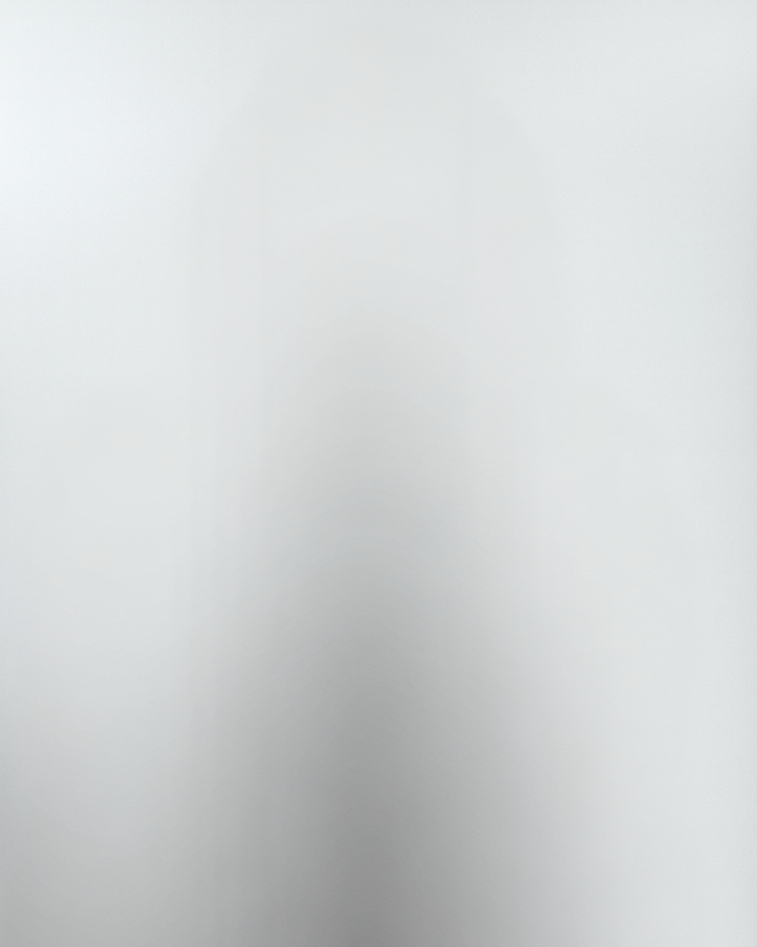 A blank white wall with subtle shadows and no visible objects or details.