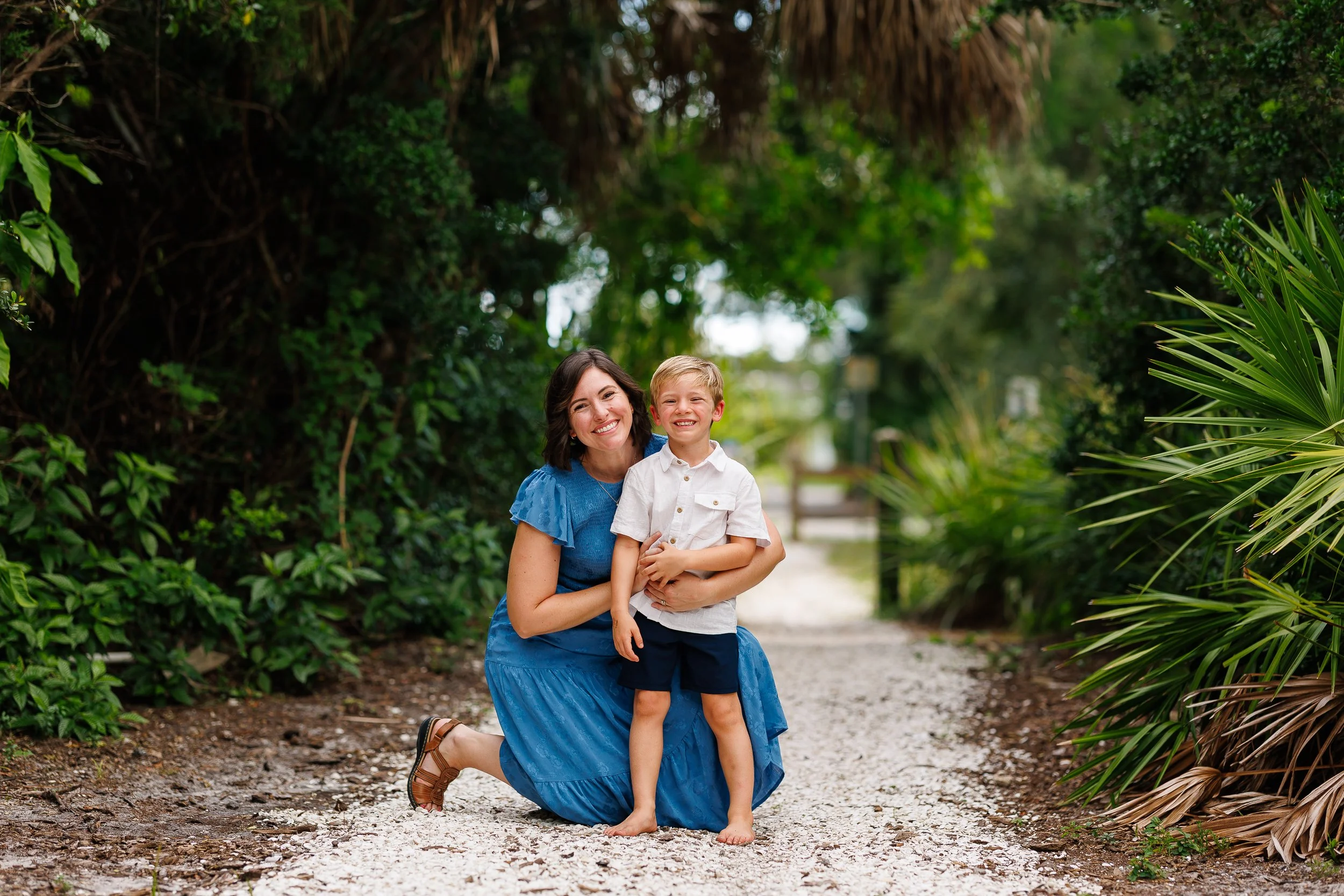 A parent holding a child on a gravel path at Phillippi Estate Park in Sarasota