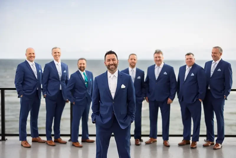 Groom portrait with groomsmen at oceanfront wedding venue