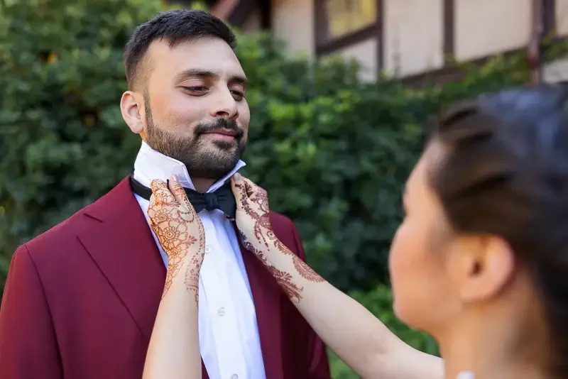 Bride adjusts groom’s bow tie during first look at Saint Clements Castle
