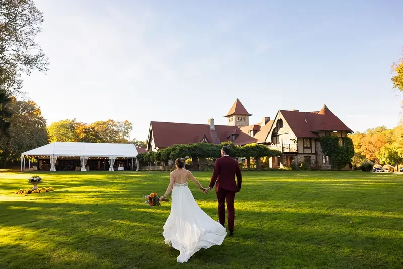 Bride and groom walking across lawn toward Saint Clements Castle wedding reception