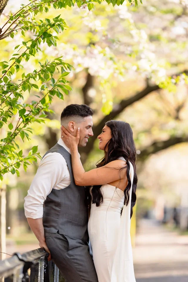 Engaged couple embracing beneath spring greenery in Wooster Square Park