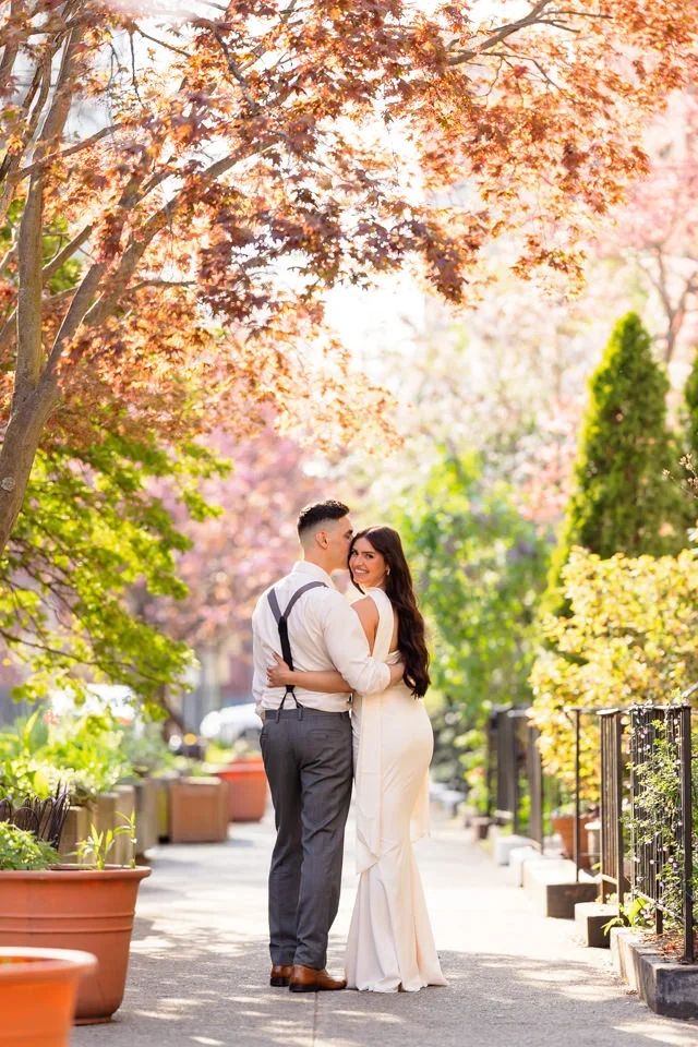 Engaged couple walking under cherry blossoms in Wooster Square Park