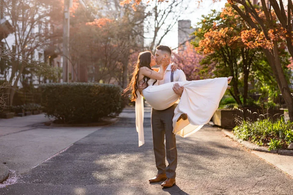 Couple lifted beneath cherry blossoms during spring engagement session