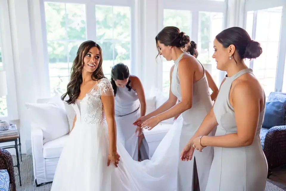 bridesmaids-helping-bride-with-wedding-dress.webp