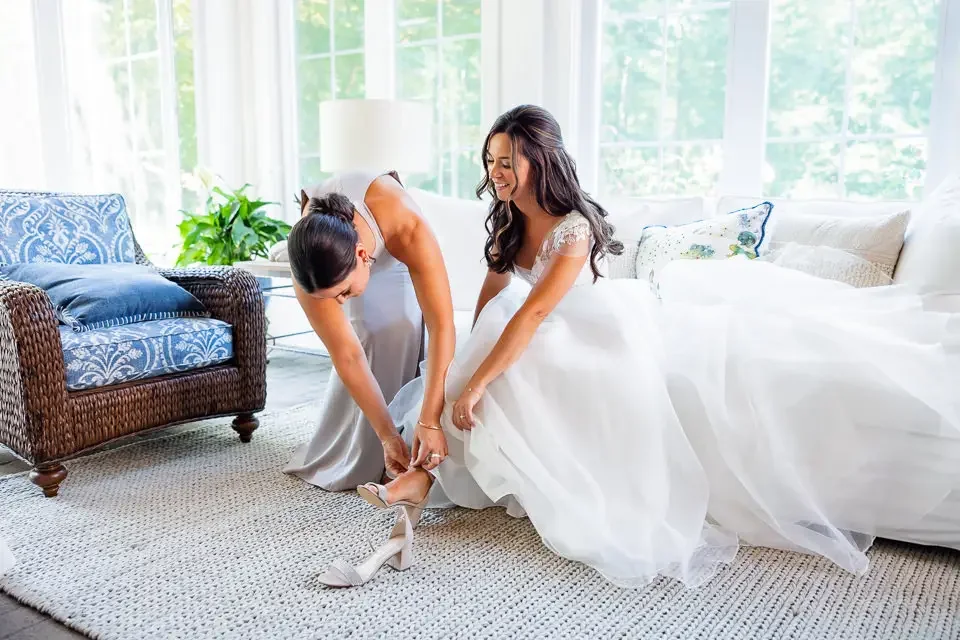bridesmaid-helping-bride-with-wedding-shoes.webp