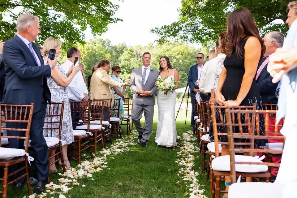 bride-walking-down-outdoor-aisle-with-father.webp