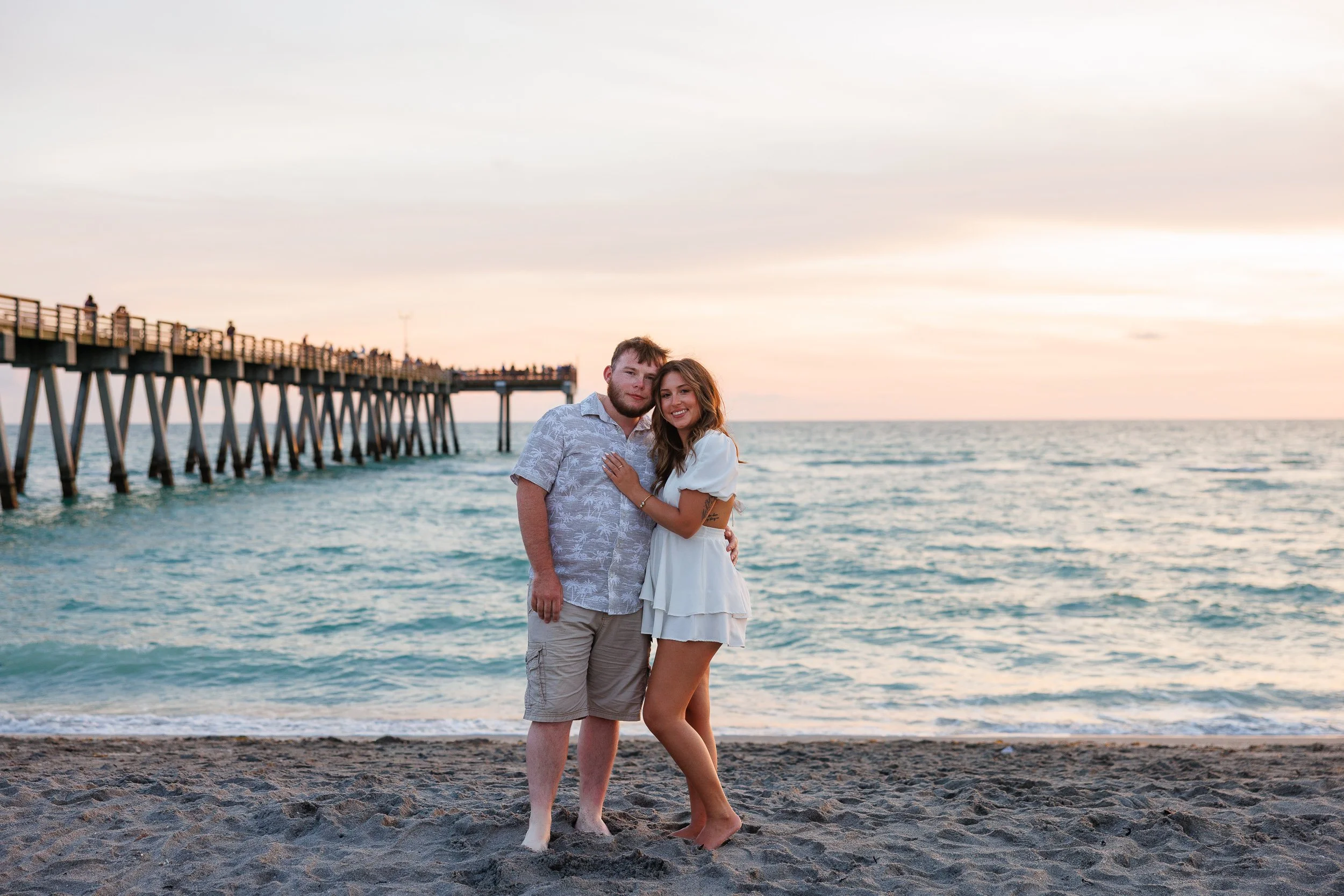 03-couple-standing-together-beach-sunset-pier.jpg